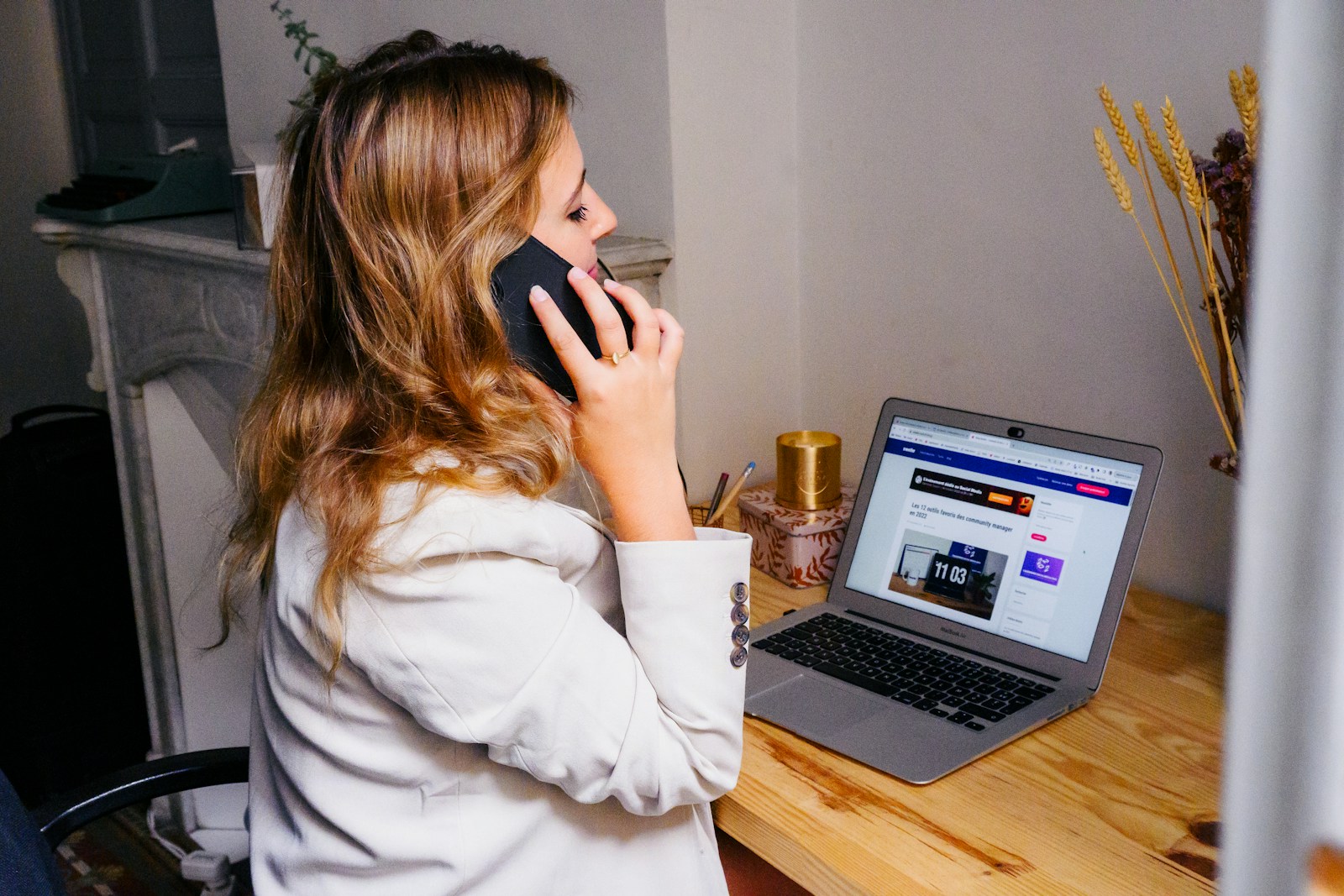 Photo by Swello a woman sitting at a desk with a laptop and a phone